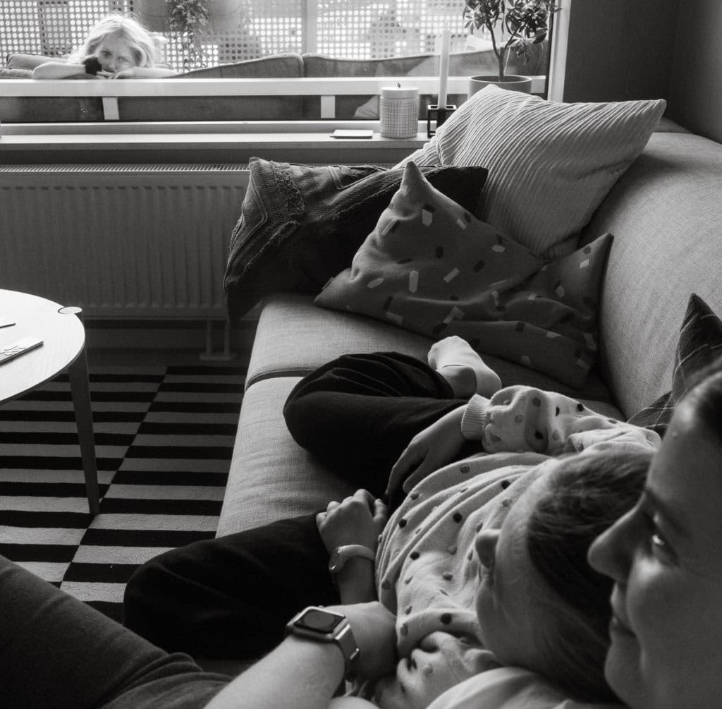 Barn og hund på sofaen i et koselig hjemmemiljø.